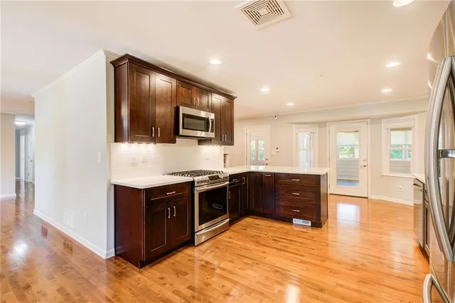 a kitchen with stainless steel appliances granite countertop a refrigerator a sink and white cabinets with wooden floor