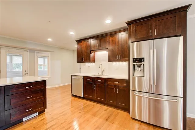 a kitchen with stainless steel appliances kitchen island granite countertop a table chairs sink and cabinets