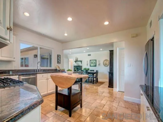 5512 Candlelight Drive La Jolla, CA 92037 - Photo 10 of 23 a kitchen with stainless steel appliances granite countertop table chairs sink and cabinets