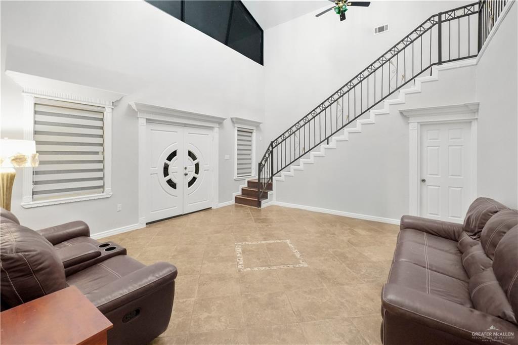 5051 Iowa Road Penitas, TX 78576 - Photo 10 of 10 Living area with stairway, baseboards, a towering ceiling, ceiling fan, and tile patterned flooring