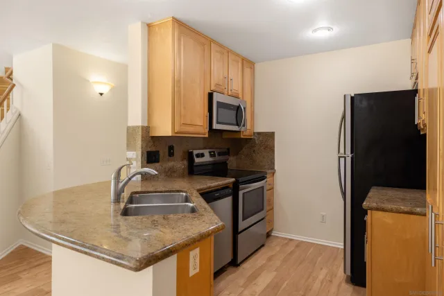 a kitchen with stainless steel appliances granite countertop a sink a stove and a refrigerator