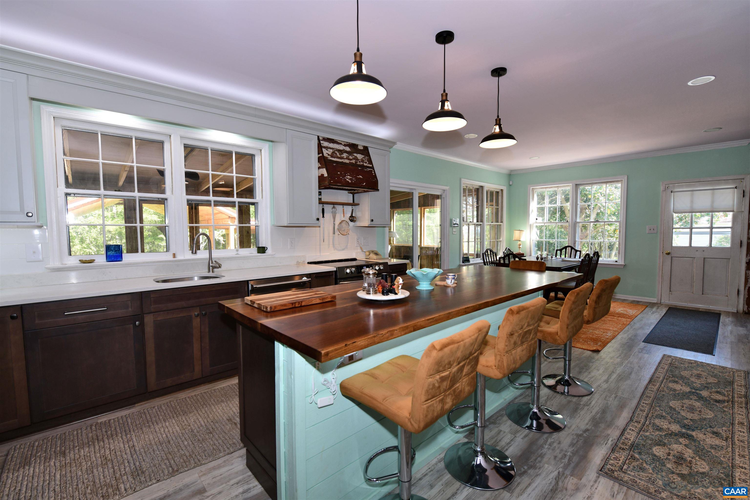 879 Evans Mill Road Dillwyn, VA 23936 - Photo 13 of 43 a kitchen with a stove a sink dishwasher a dining table and chairs with wooden floor