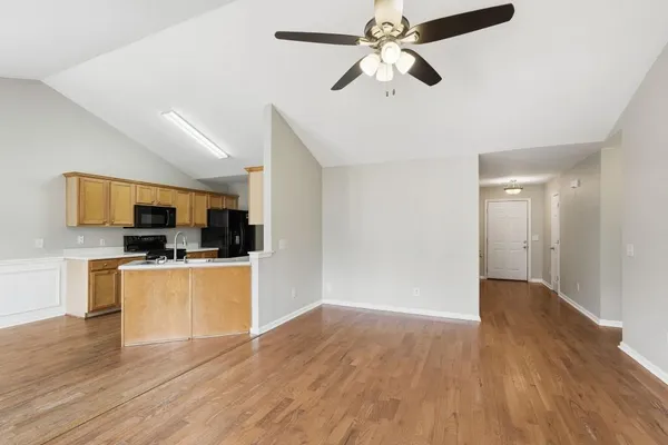 a open kitchen with stainless steel appliances kitchen island a wooden floor and white cabinets