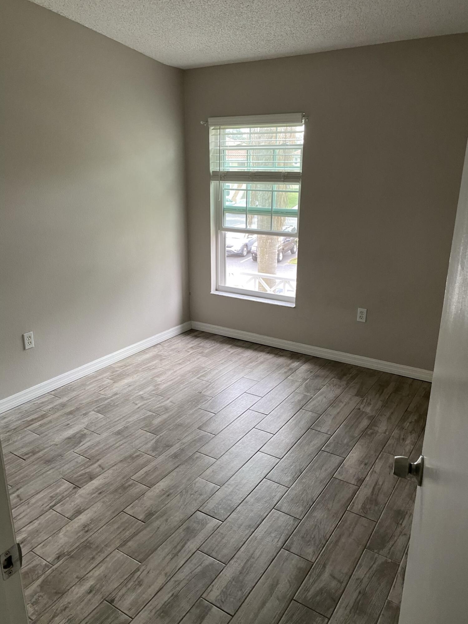 2836 Osprey Cove Place, Unit 201 Kissimmee, FL 34746 - Photo 8 of 11 an empty room with wooden floor and windows