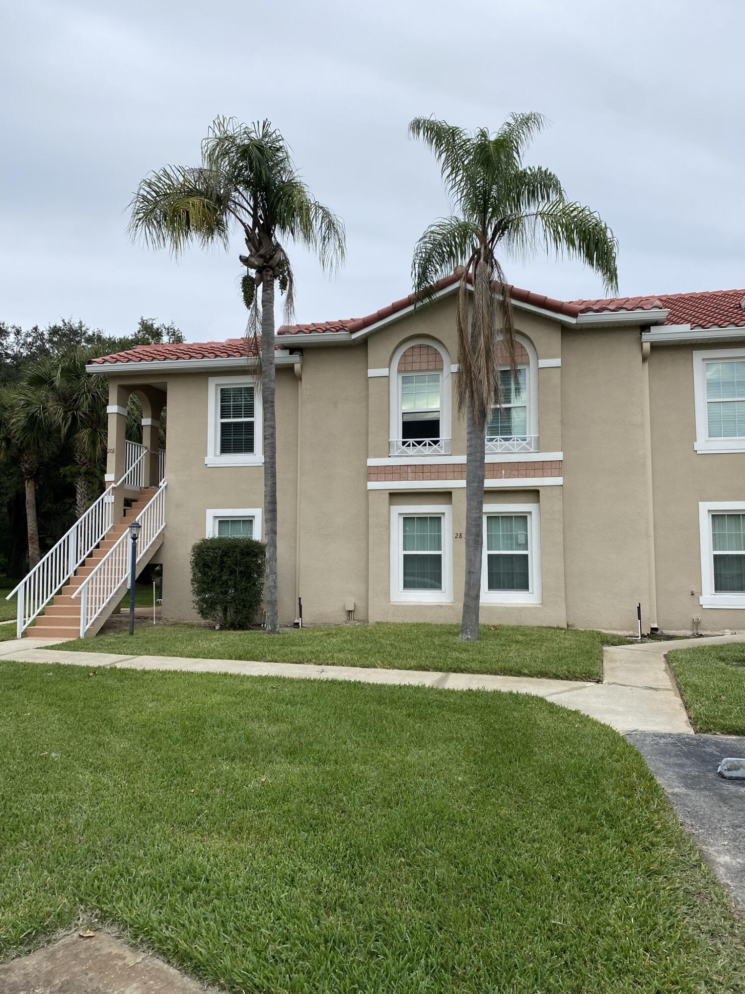 2836 Osprey Cove Place, Unit 201 Kissimmee, FL 34746 - Photo 9 of 11 a front view of a house with a yard and palm trees
