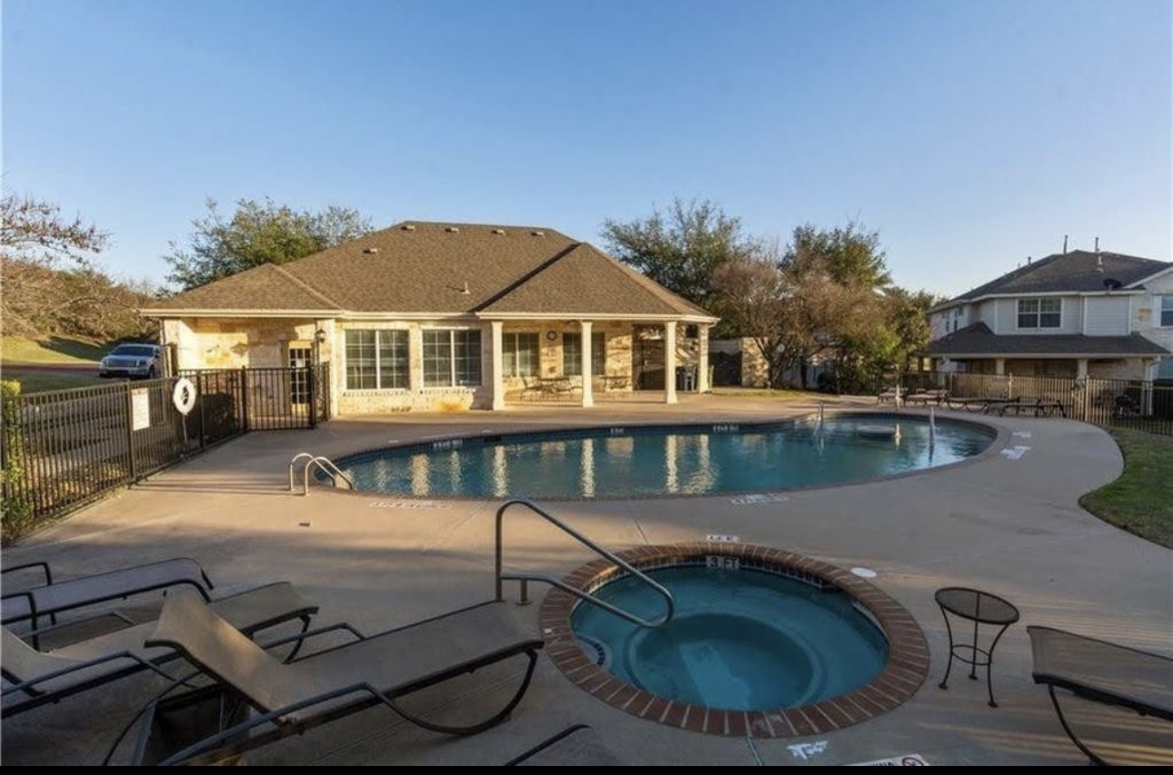 1900 Scofield Ridge Parkway, Unit 3101 Austin, TX 78727 - Photo 24 of 24 Swimming pool with an integrated spa, surrounded by a concrete deck and a stone-clad clubhouse featuring multiple windows and a covered patio