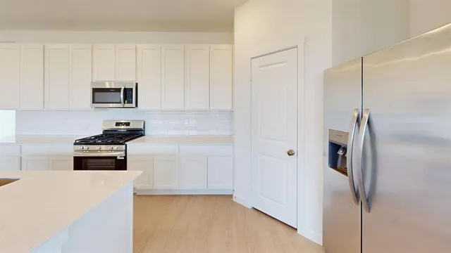 a kitchen with stainless steel appliances granite countertop white cabinets and refrigerator