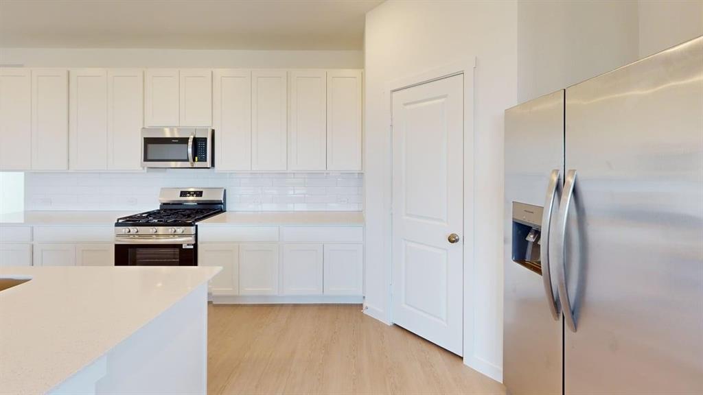454 Ridge Drive Justin, TX 76247 - Photo 4 of 24 a kitchen with stainless steel appliances granite countertop white cabinets and refrigerator