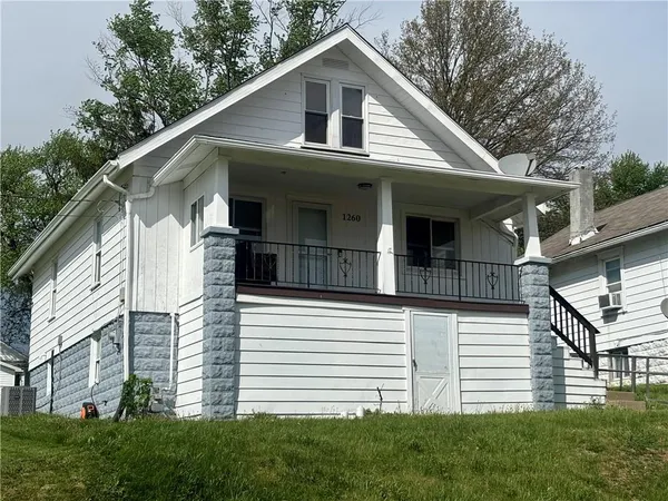 a view of a white house with large windows and a small yard