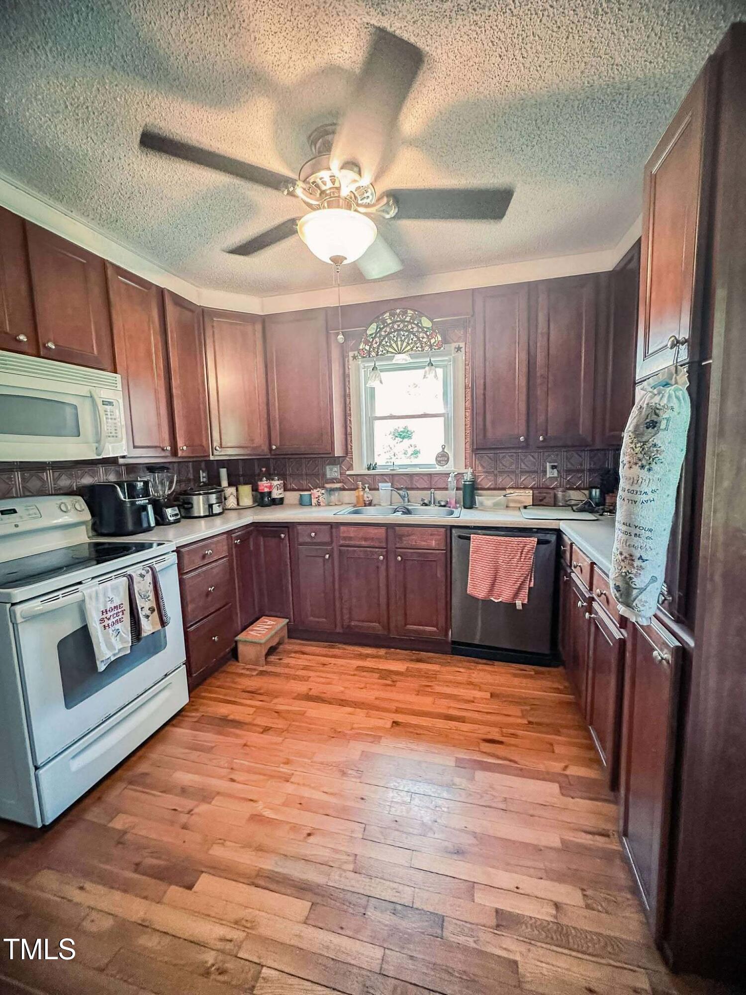 8683 Highway 15 Bullock, NC 27507 - Photo 13 of 36 a large kitchen with stainless steel appliances granite countertop a stove top oven a sink dishwasher and cabinets with wooden floor