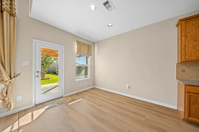 a view of an empty room with window and wooden floor