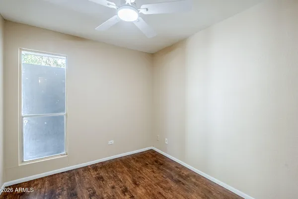 an empty room with a chandelier fan and wooden floor