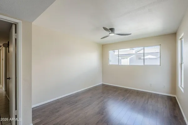 an empty room with wooden floor chandelier and windows