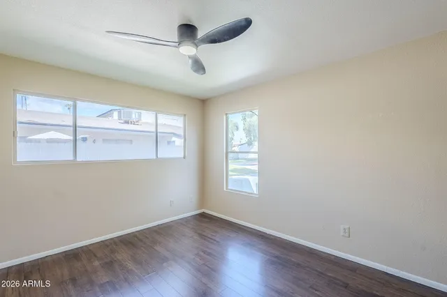 a view of empty room with wooden floor and fan