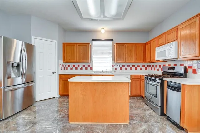 a kitchen with stainless steel appliances granite countertop a refrigerator a sink dishwasher a stove with wooden cabinets and floor