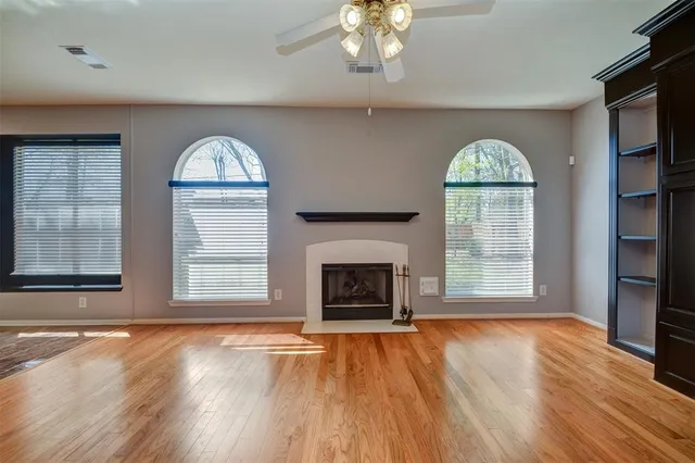 an empty room with fireplace wooden floor and windows