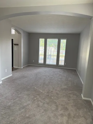 a view of a big room with windows and chandelier fan