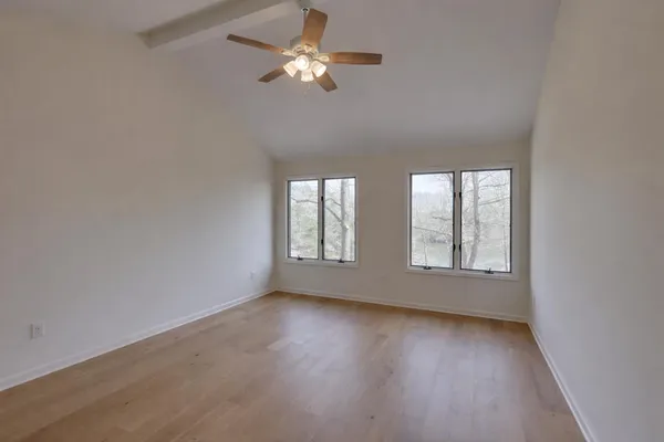 a view of an empty room with a window and wooden floor