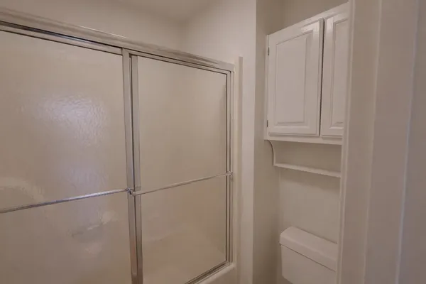 an empty room with windows and chandelier fan