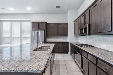 a kitchen with stainless steel appliances granite countertop a refrigerator a stove a sink and a microwave