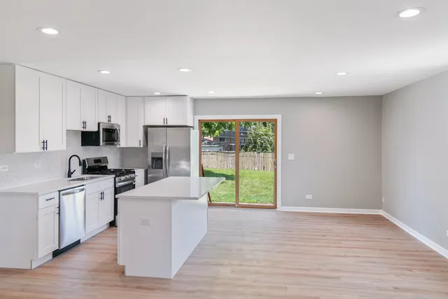 a kitchen with kitchen island a sink a stove a refrigerator cabinets and a window