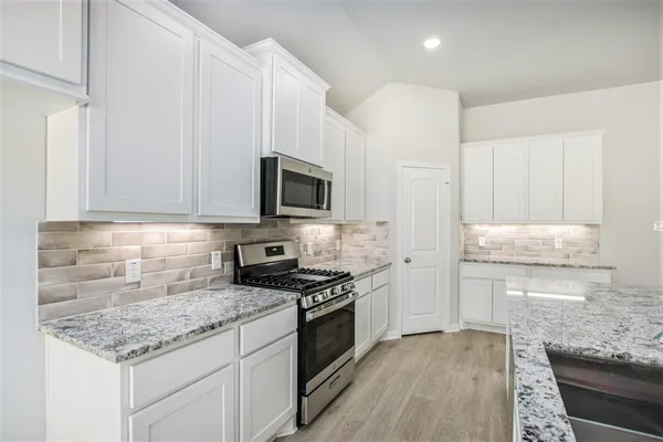 a kitchen with granite countertop a sink stove and cabinets