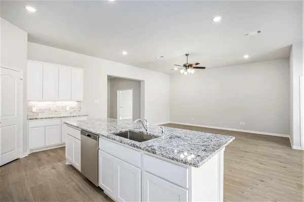 a kitchen with a sink dishwasher and white cabinets with wooden floor