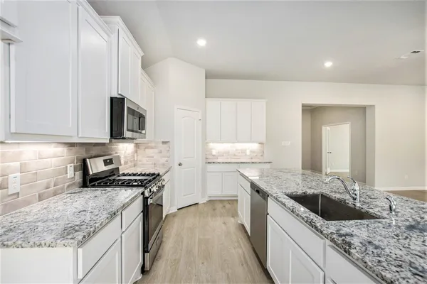 a kitchen with stainless steel appliances granite countertop a sink stove and refrigerator