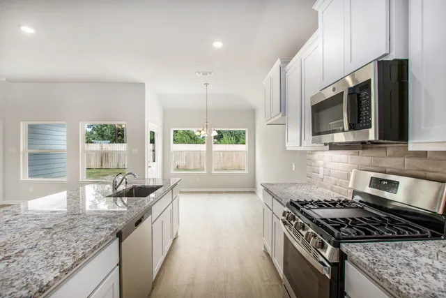 a kitchen with stainless steel appliances granite countertop a stove a sink and a microwave