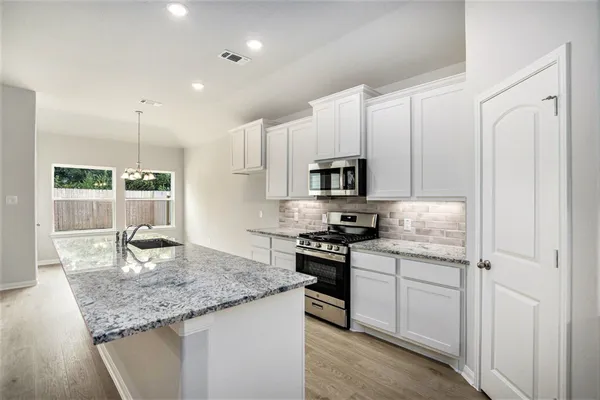 a kitchen with stainless steel appliances granite countertop a sink stove and refrigerator