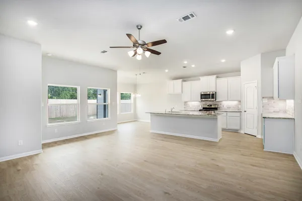 a large kitchen with stainless steel appliances kitchen island a large counter top and a wooden floors