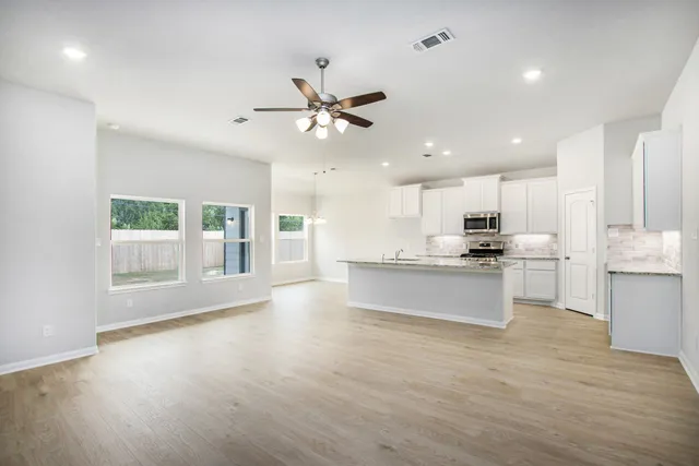a large kitchen with stainless steel appliances kitchen island a large counter top and a wooden floors