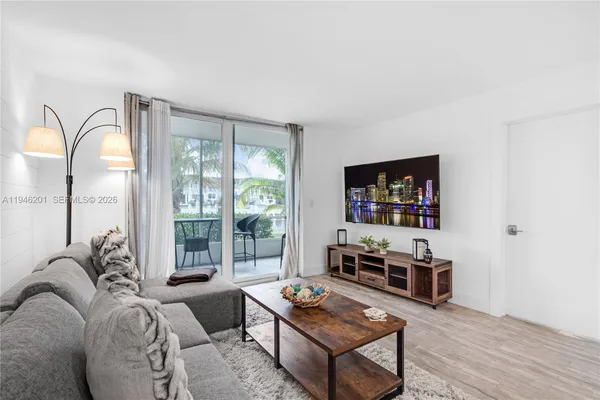 a living room with furniture a flat screen tv and a floor to ceiling window