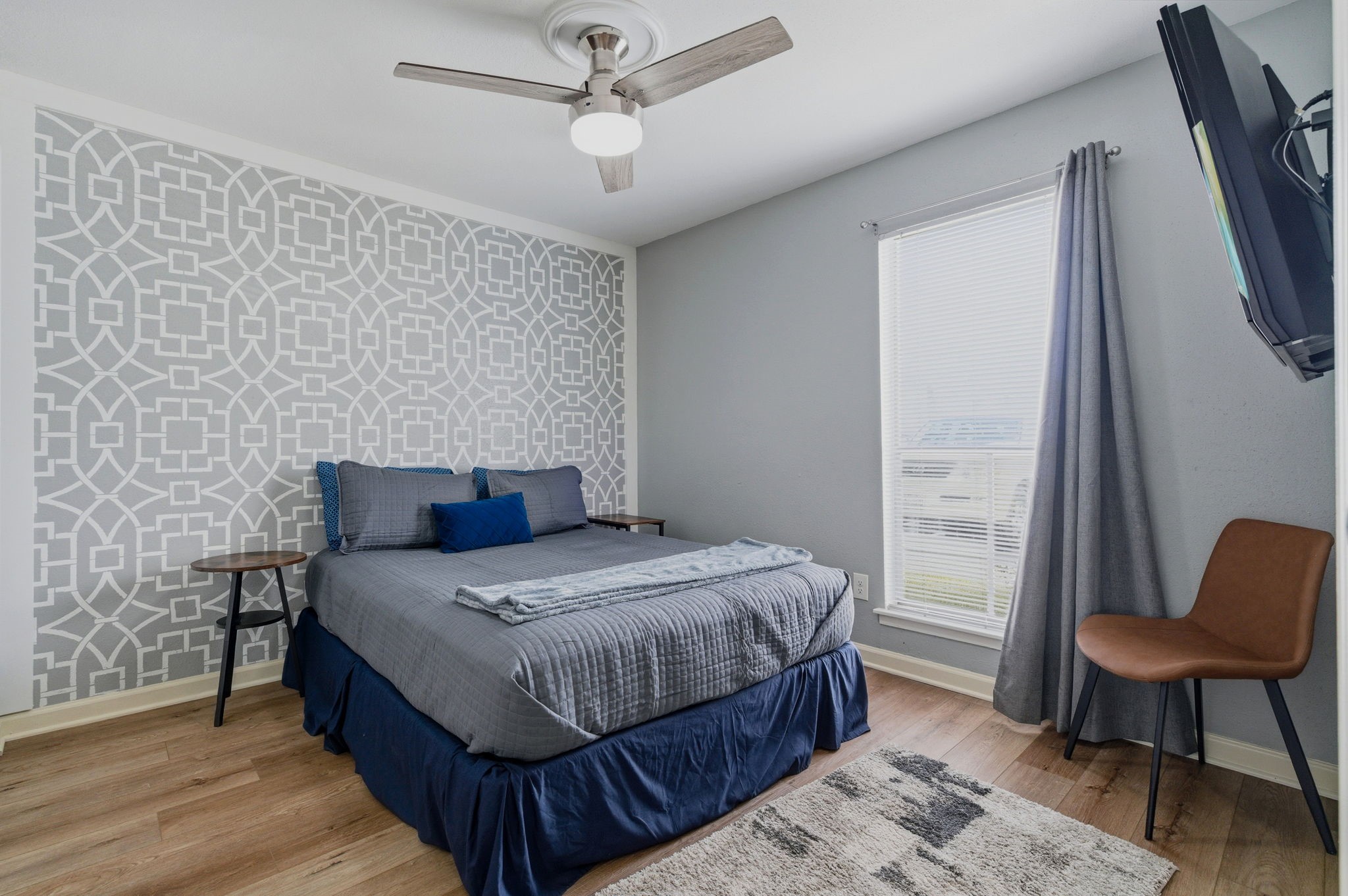 13151 Walden Road, Unit 127 Montgomery, TX 77356 - Photo 17 of 46 a bedroom with a bed a chair and potted plant on the wooden floor