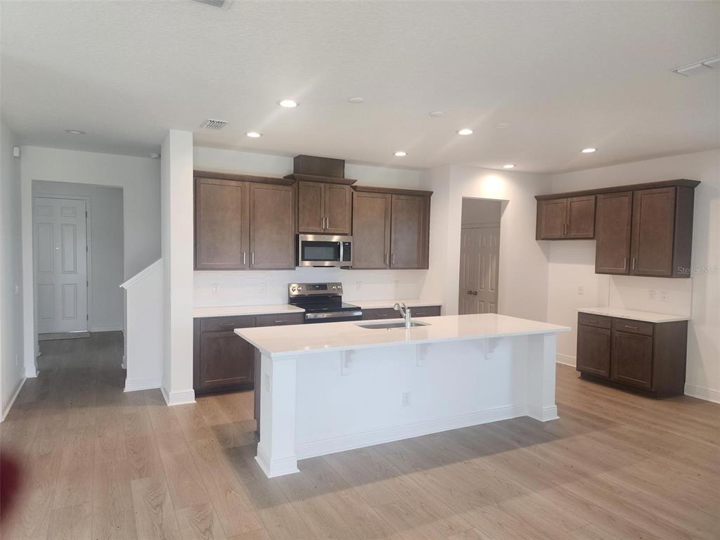7501 Catania Loop Clermont, FL 34714 - Photo 3 of 12 a large kitchen with stainless steel appliances a large counter top a stove and a refrigerator