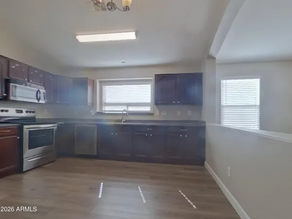 a kitchen with stainless steel appliances granite countertop a refrigerator a sink dishwasher a stove and white countertops with wooden floor