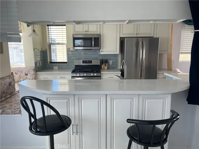 a kitchen with stainless steel appliances a dining table chairs microwave and sink
