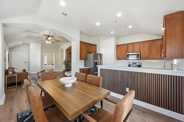 a view of a dining room and livingroom with furniture wooden floor a rug a fireplace and a chandelier