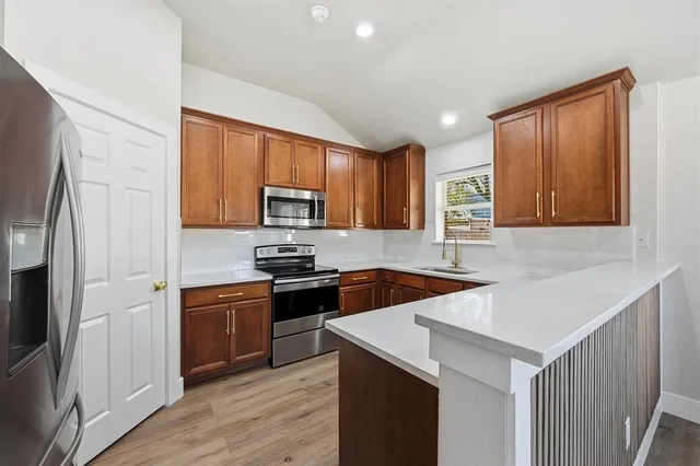 a kitchen with granite countertop a stove top oven a sink dishwasher and a refrigerator with wooden floor