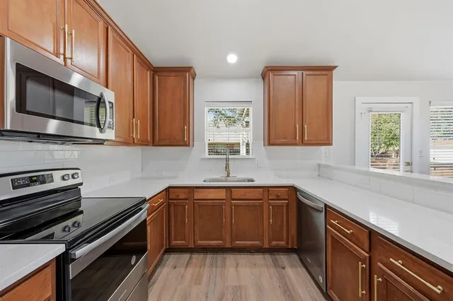 a kitchen with stainless steel appliances a sink a stove cabinets and a microwave oven