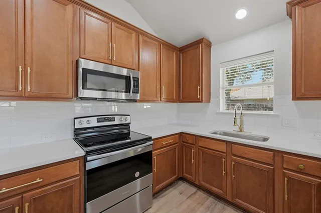 a kitchen with sink a microwave a stove and cabinets