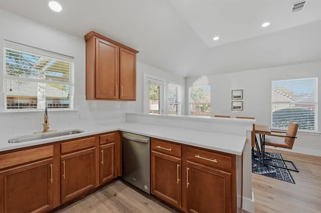 a kitchen with stainless steel appliances granite countertop wooden cabinets a sink a stove a dining table and chairs