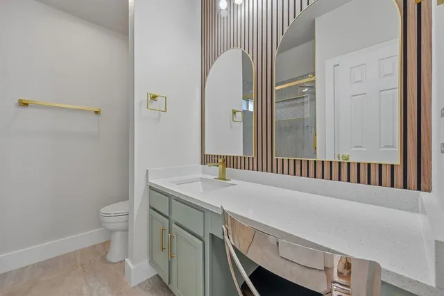 a en suite bathroom with a granite countertop sink and a toilet