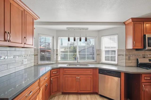 a kitchen with granite countertop a sink a stove and cabinets