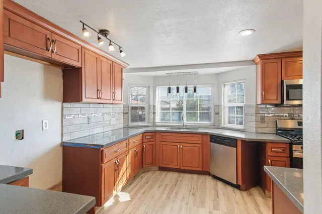 a kitchen with stainless steel appliances granite countertop a sink and wooden cabinets