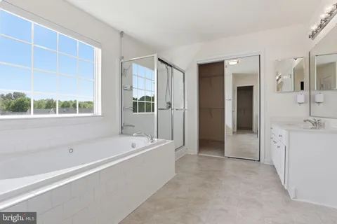 a spacious bathroom with a tub sink and mirror