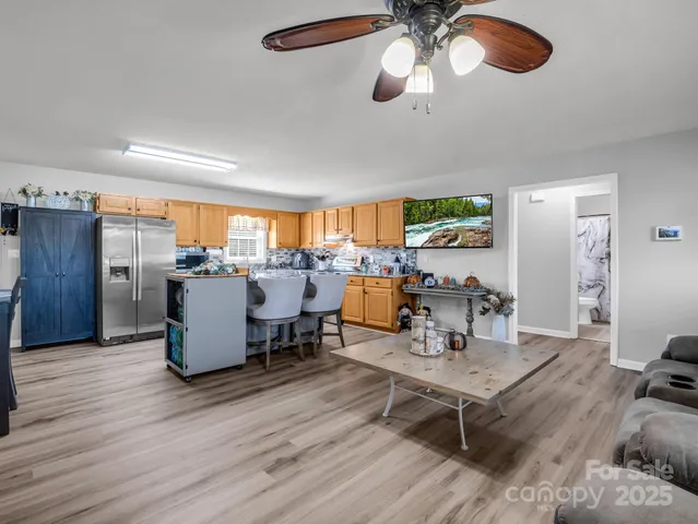 a room with stainless steel appliances kitchen island granite countertop a table chairs and a refrigerator