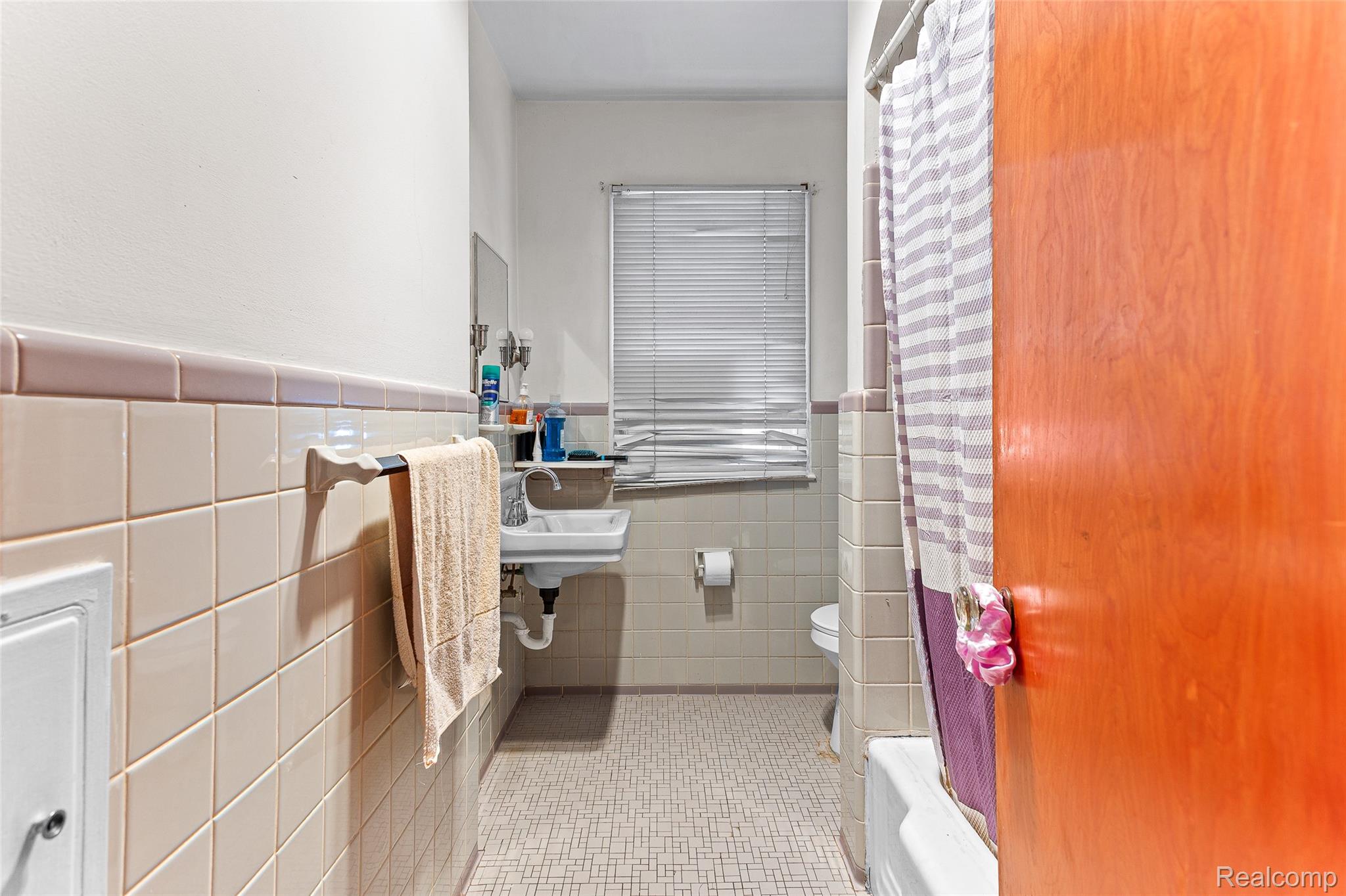 1830 North Gulley Road Dearborn, MI 48128 - Photo 26 of 29 Bathroom with tile walls, a wainscoted wall, light tile patterned flooring, and shower / bath combo with shower curtain