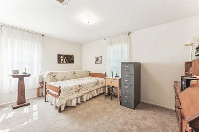 a spacious bedroom with a bed and a refrigerator