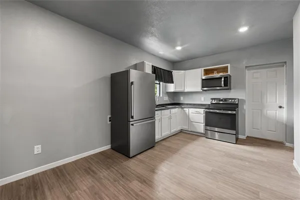 a kitchen with granite countertop a refrigerator and a stove top oven